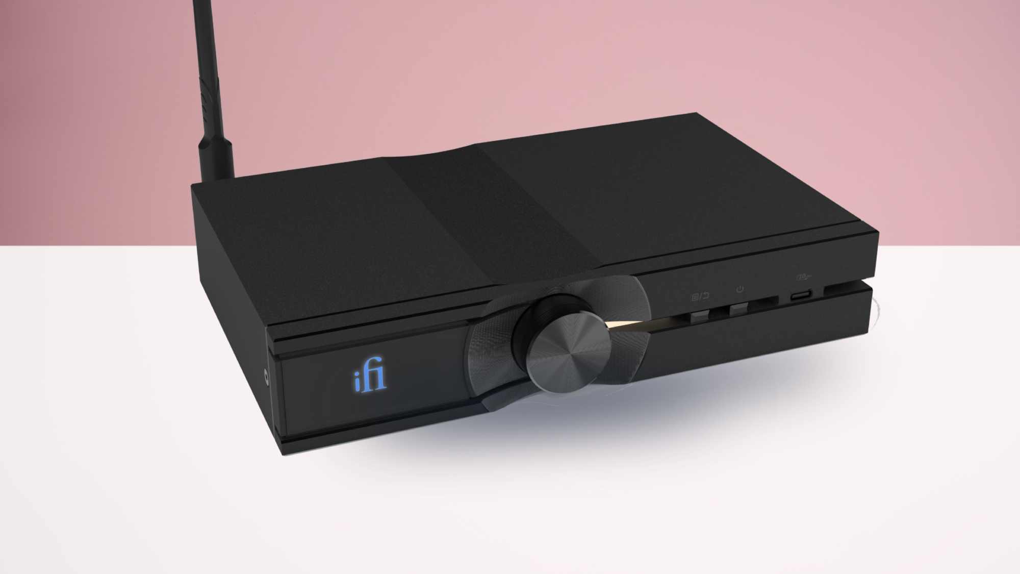 iFi Neo Stream 3 على طاولة بيضاء بخلفية وردية.