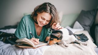 Woman writing in diary next to dog