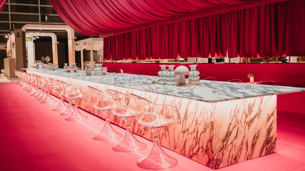 A room with pink curtain drapings and a 16-meter-long marble table with a row of transparent stools along the side