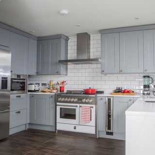 kitchen with white tiled wall grey cabinets and wooden flooring