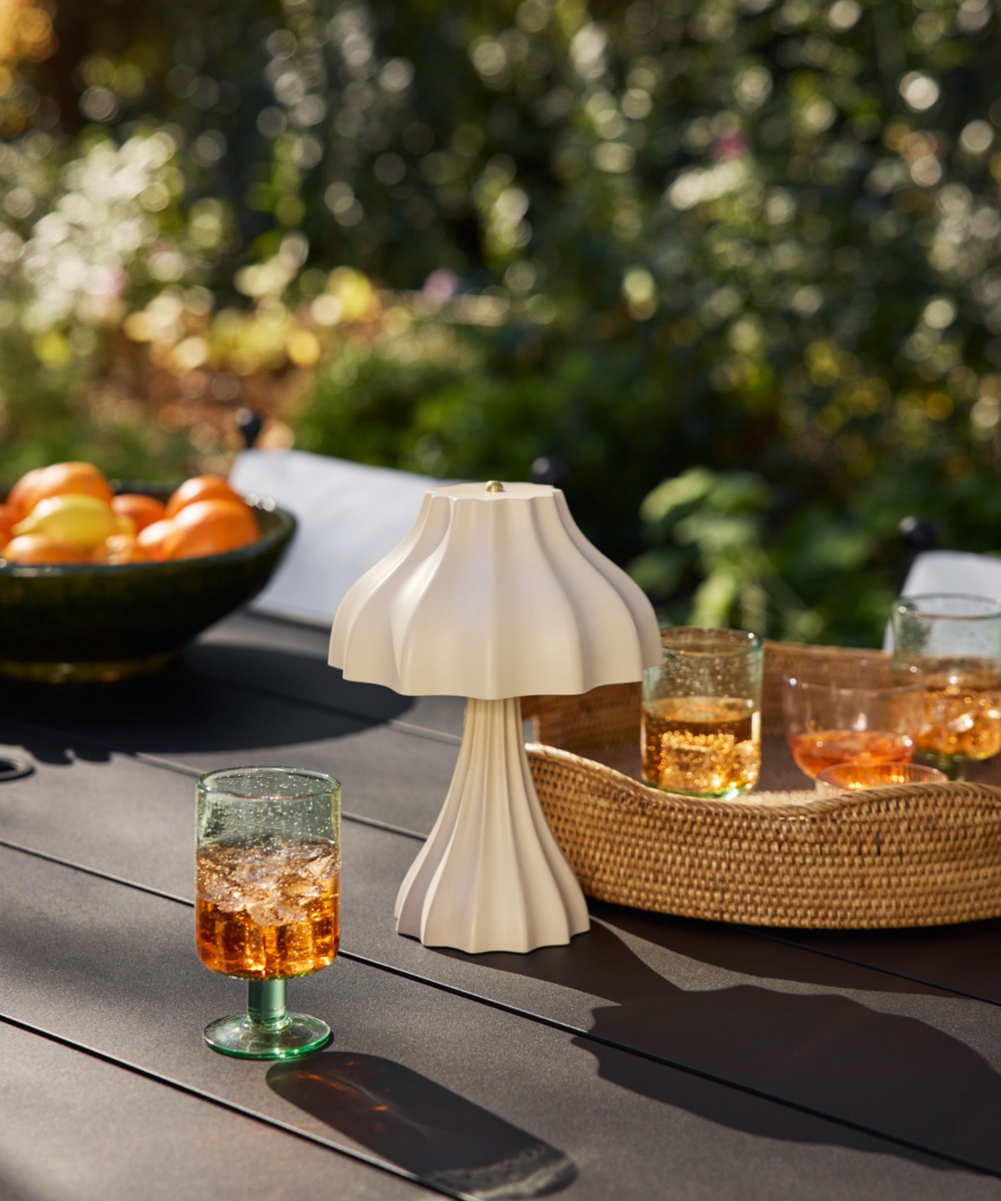 Table lamp on an outdoor table next to a rattan tray holding drinks