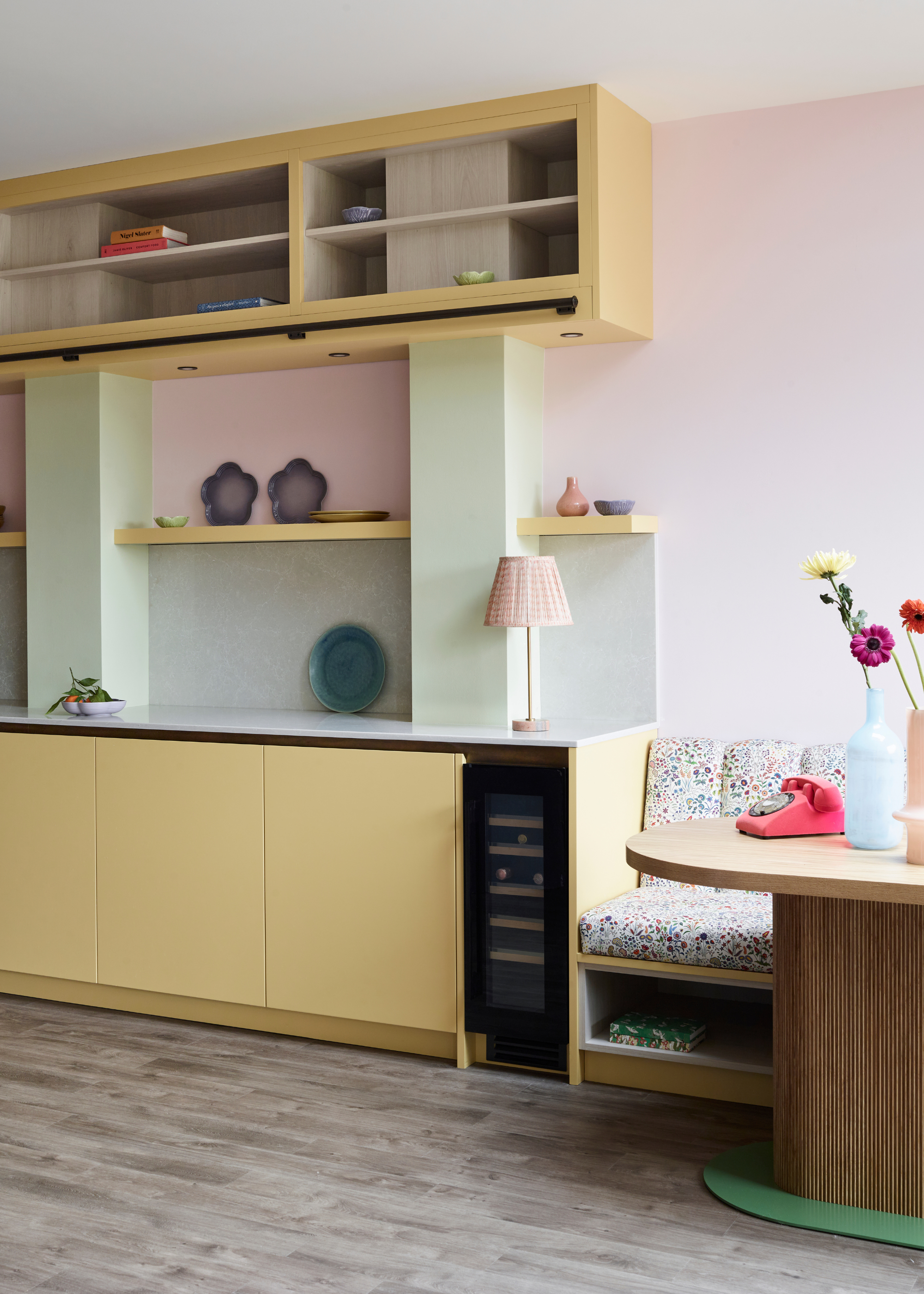 pastel-toned kitchen design with yellow cabinets and shelving and a small seating area off to the side