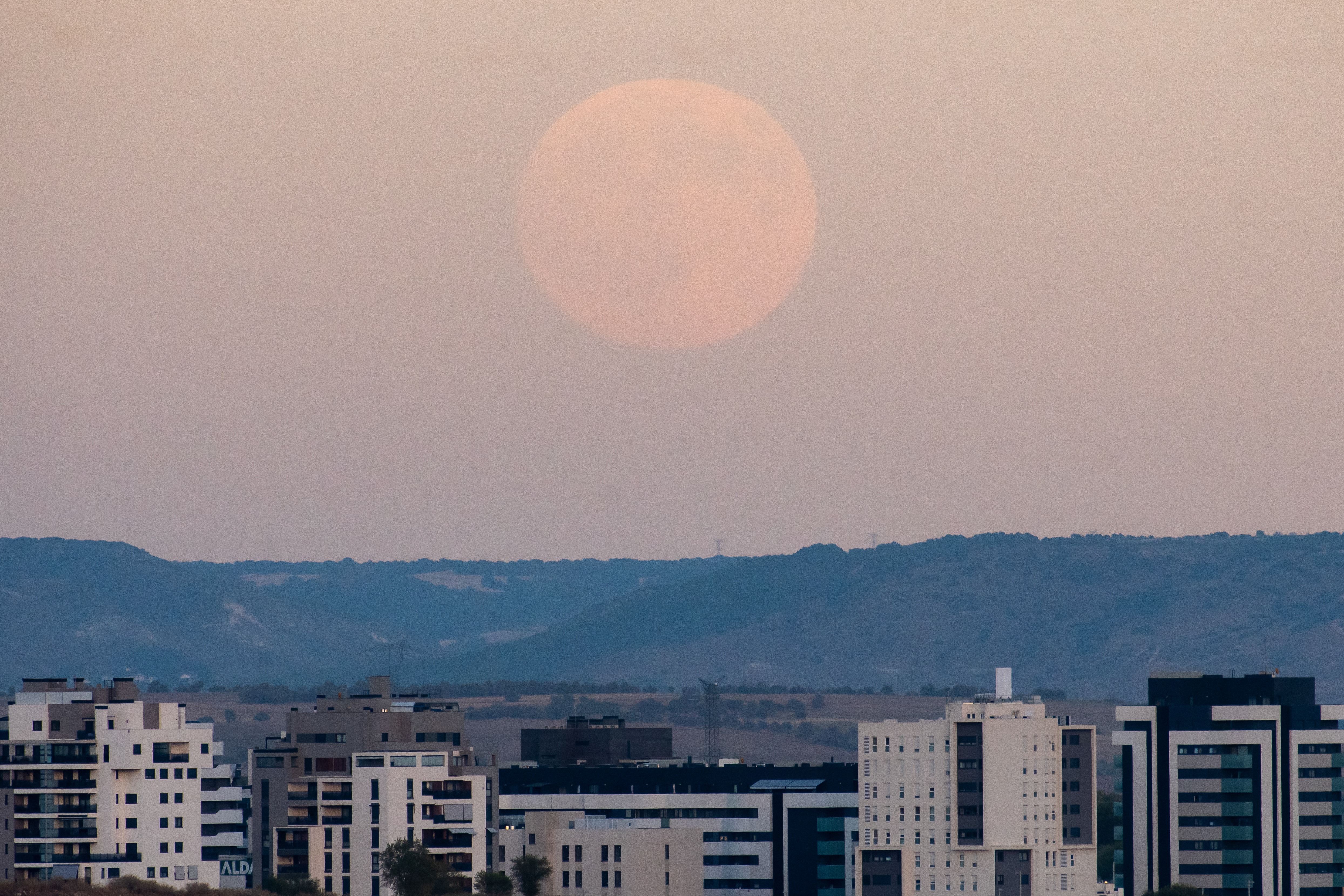 A photograph of the Harvest supermoon rising over residential buildings in Madrid, Spain.