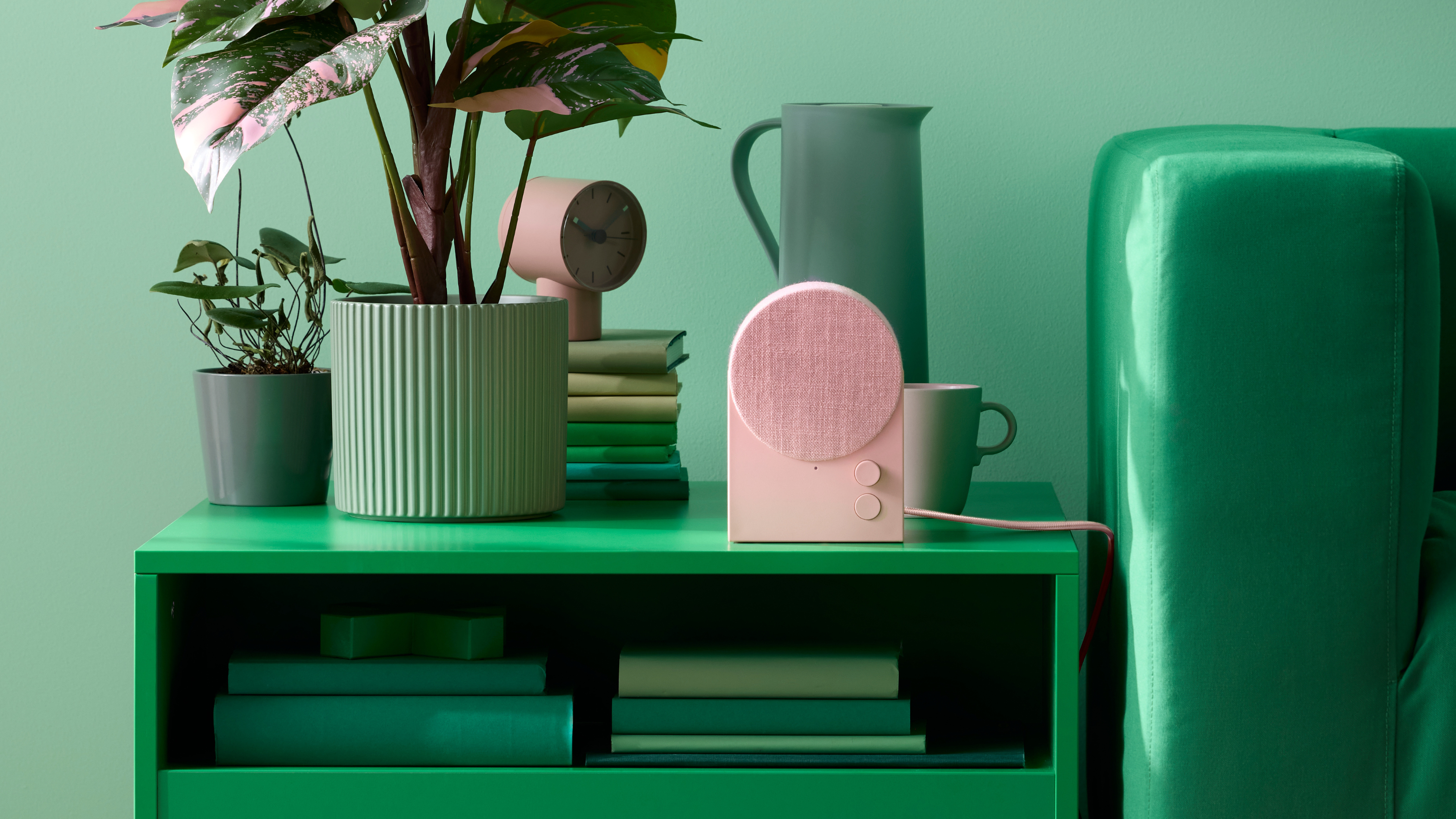 IKEA NATTBAD Speaker in Pink with an almost fully green background - green side table, wall color, sofa and accessories