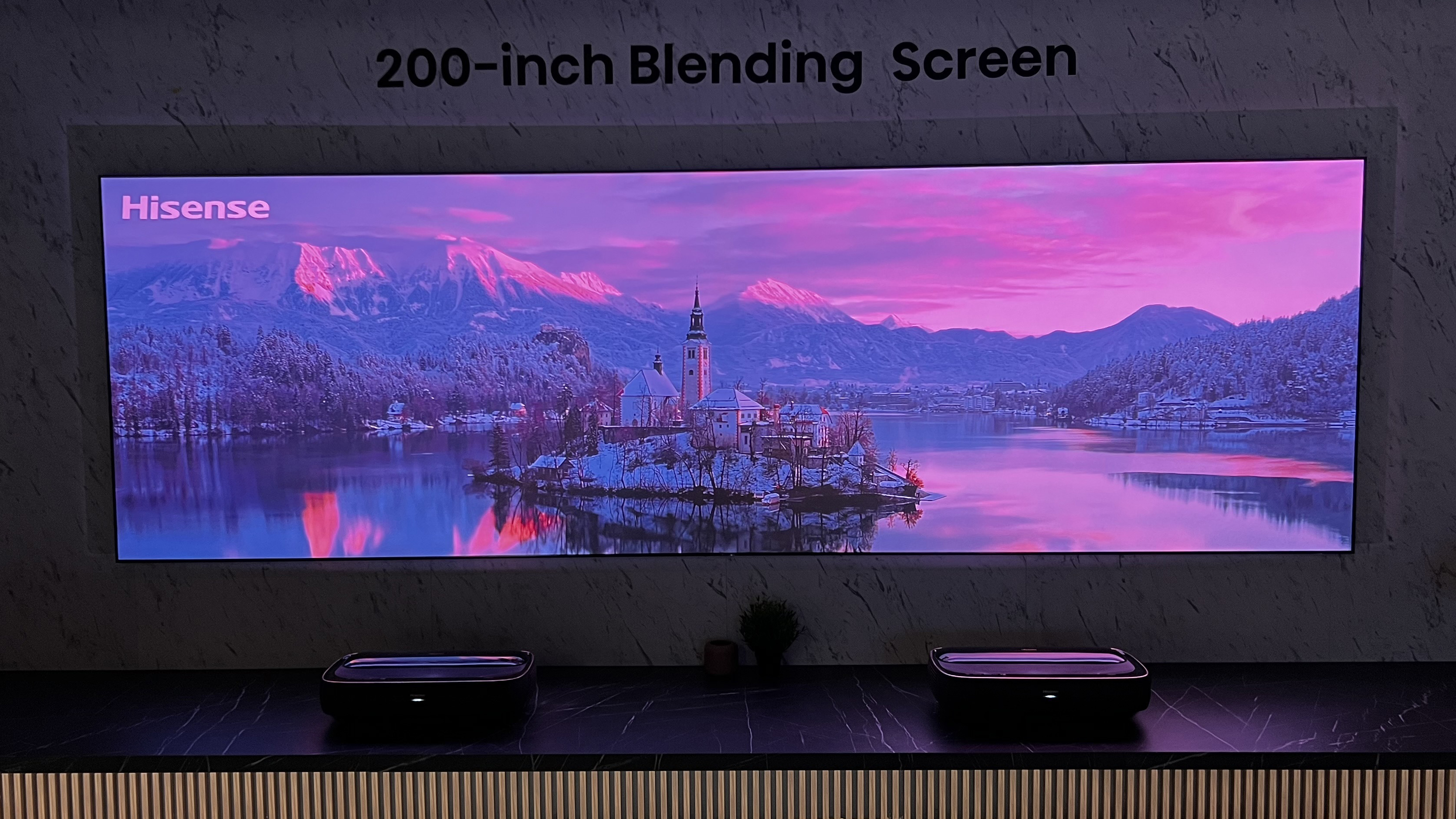 Una gran pantalla proyectada, con dos proyectores Hisense Laser TV debajo