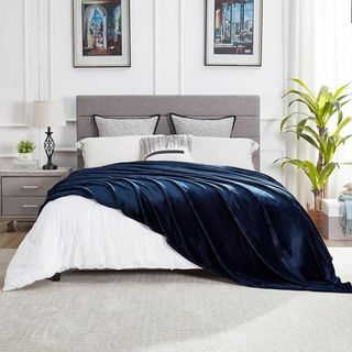 An oversized dark blue throw blanket draped across a bed