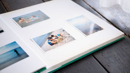 pictures of brothers playing on beach in a photo album with white pages and a blue cover. 