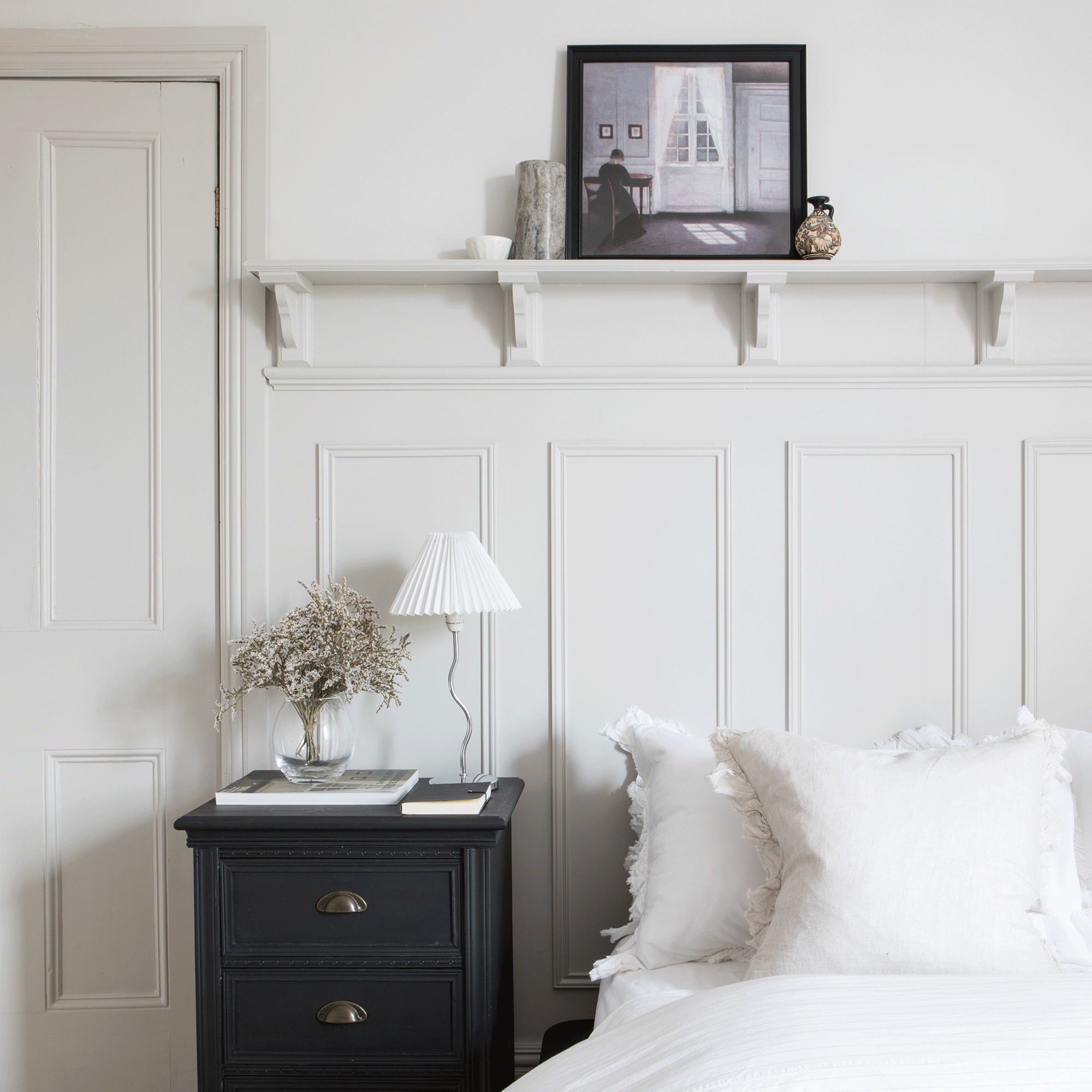 White bedroom with picture ledge and black bedside table
