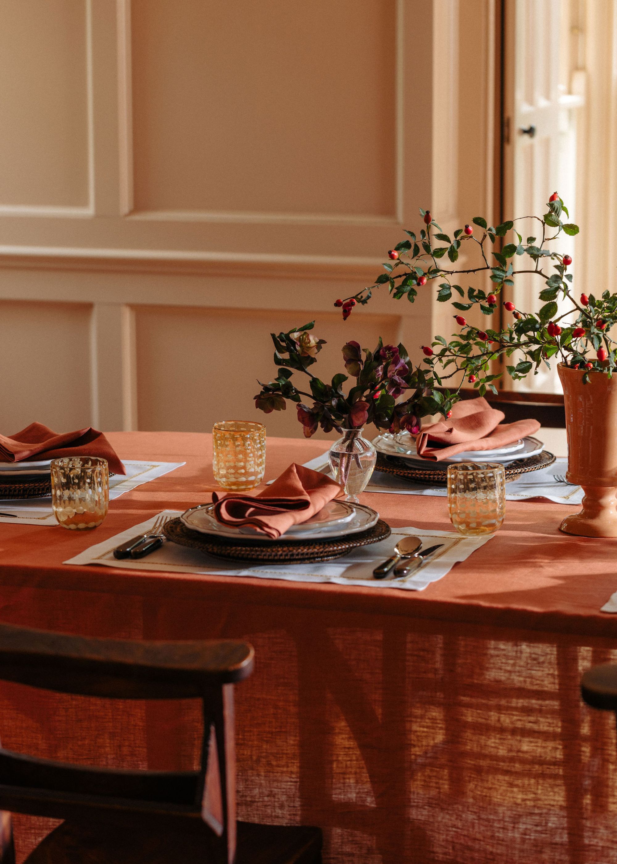 A dining table with a terracotta-colored tablecloth and modern decor.