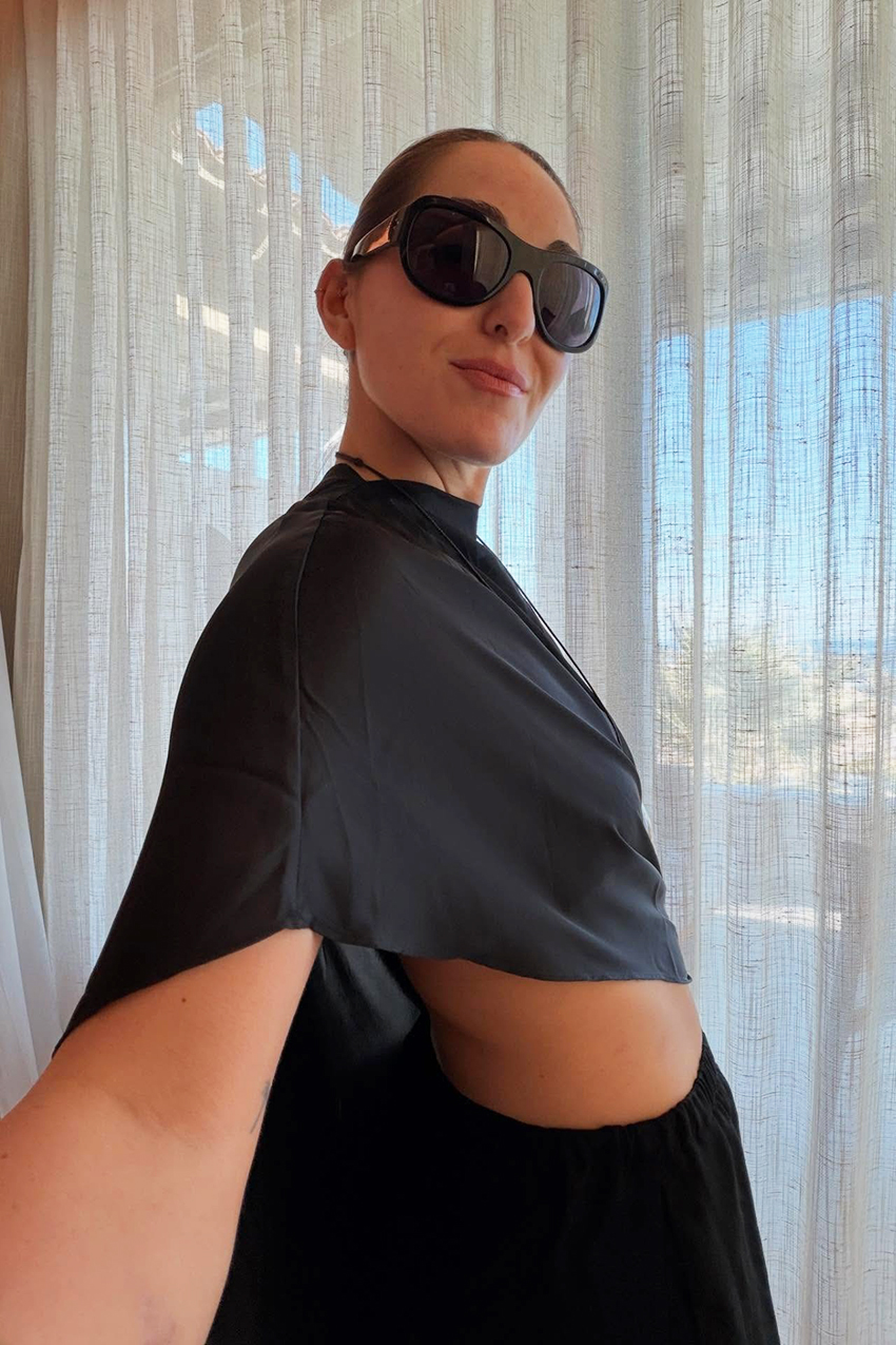 a woman wearing black sunglasses and a black satin top