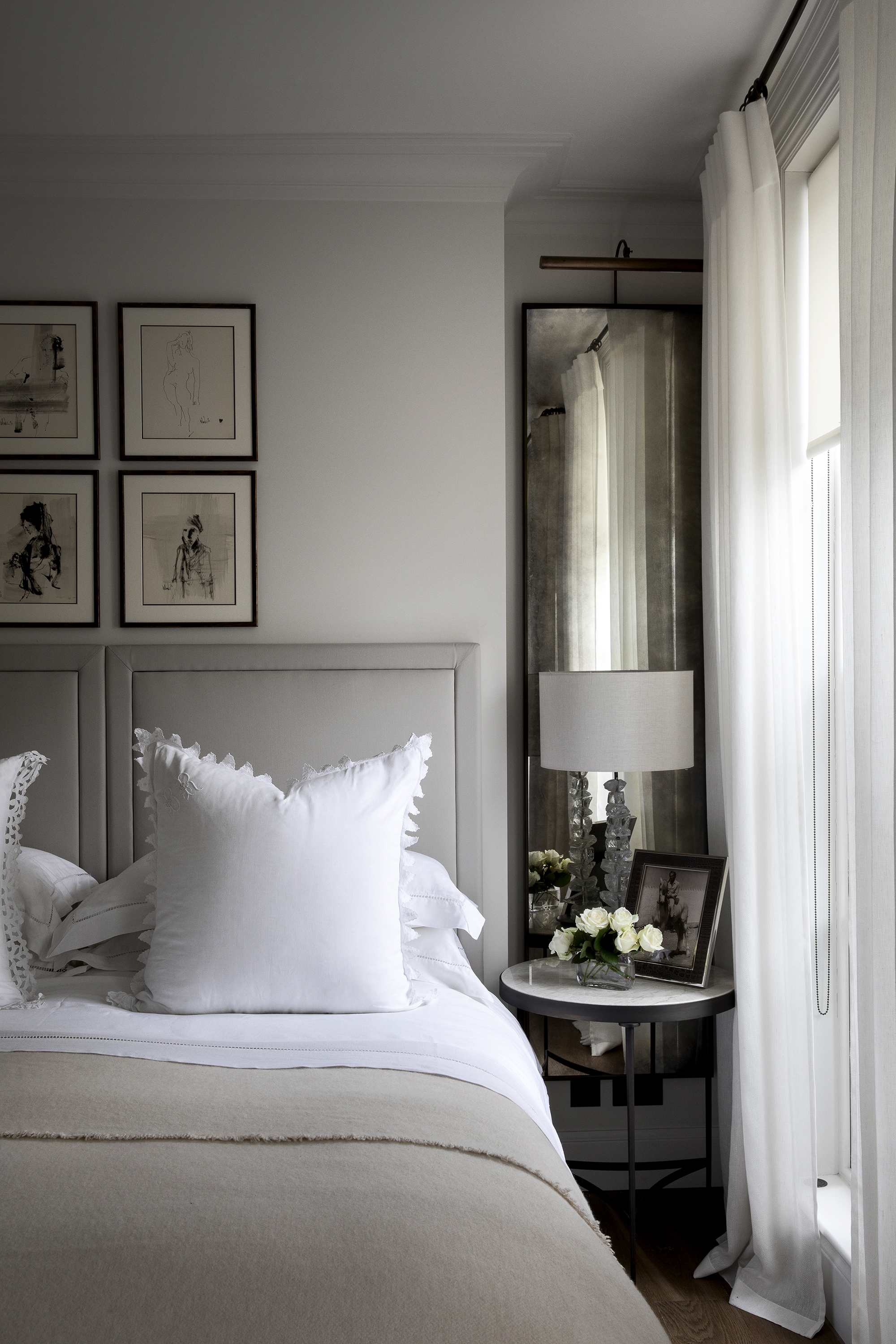 Light grey bedroom with grey headboard and mirrors in the alcoves