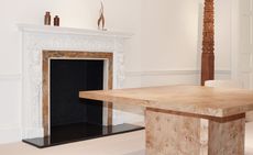 White room with fireplace, marble table and tall wooden carving