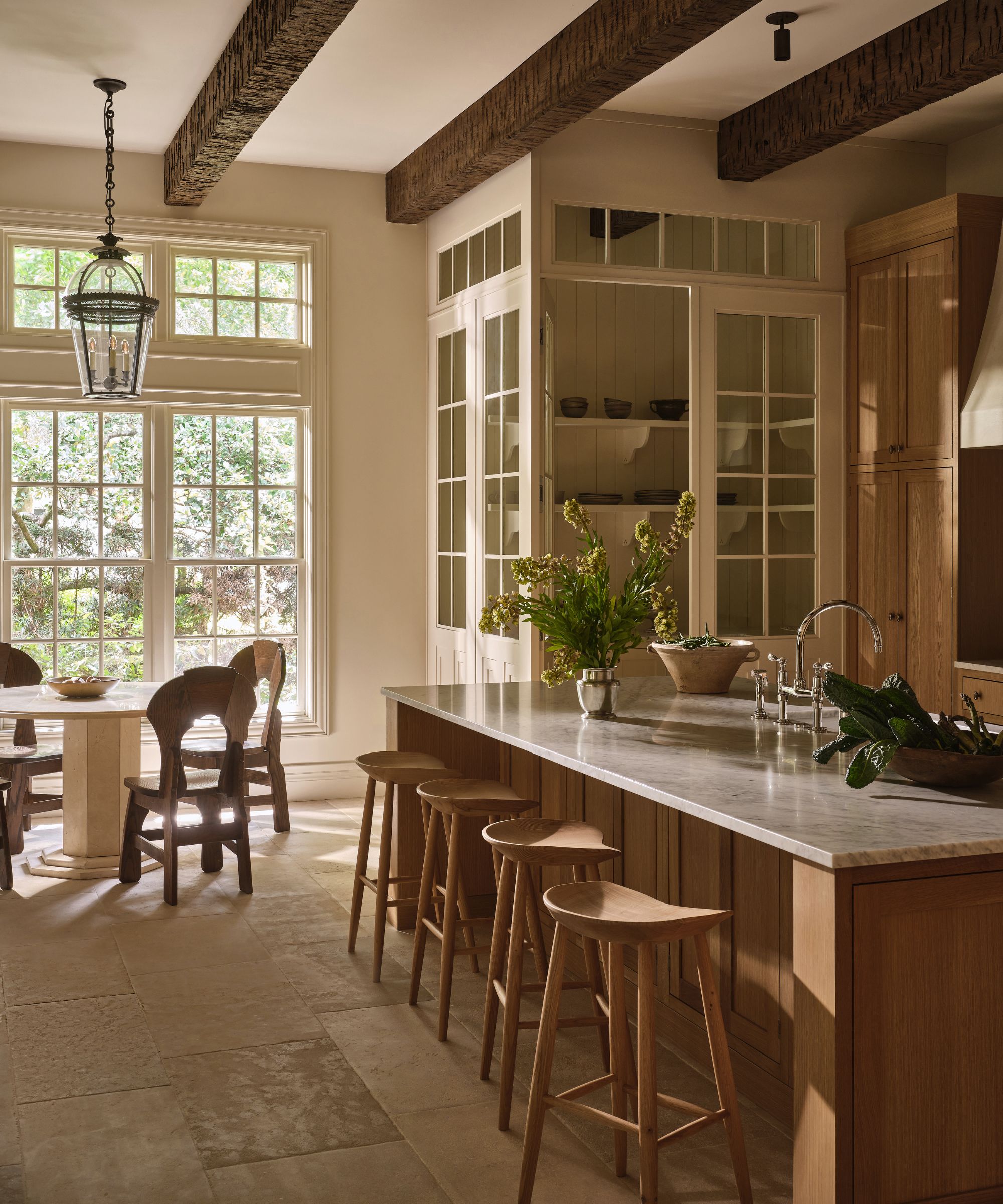 Wooden kitchen with large kitchen island, bar stool seating, pantry with glass doors, round wooden dining table