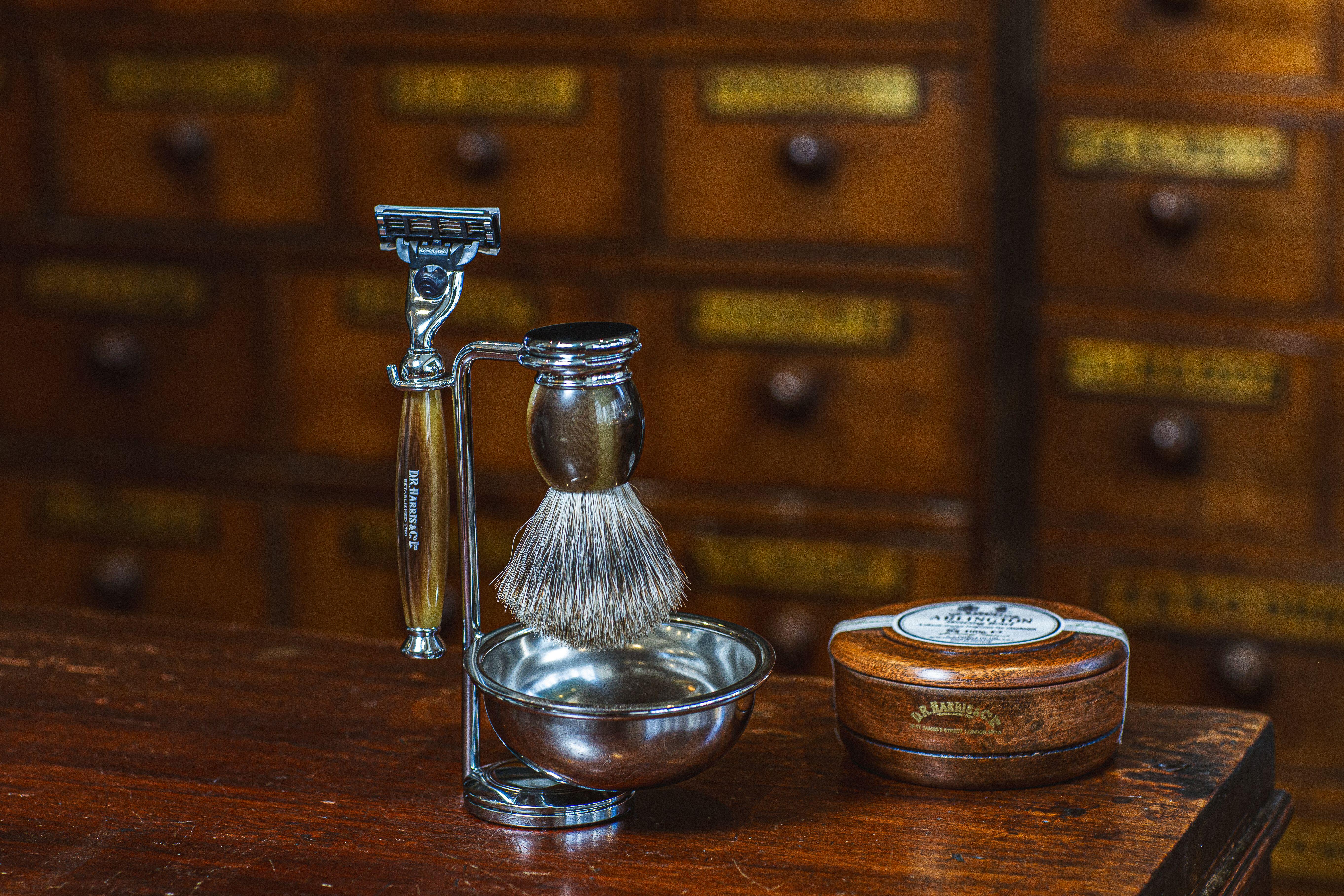 A silver stand holding a razor and shaving brush