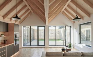 Living space with wood ceilings, a cream sofa and large windows of a Spencer Courtyard home