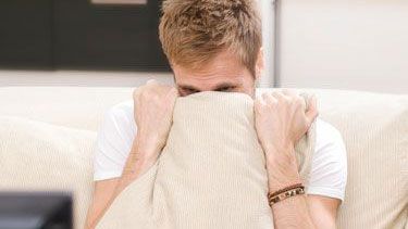 Man hiding behind a pillow