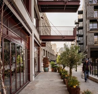 The Brentford Project showing brick residential blocks with large balconies and warehouse inspired streets and public spaces that step down to the water