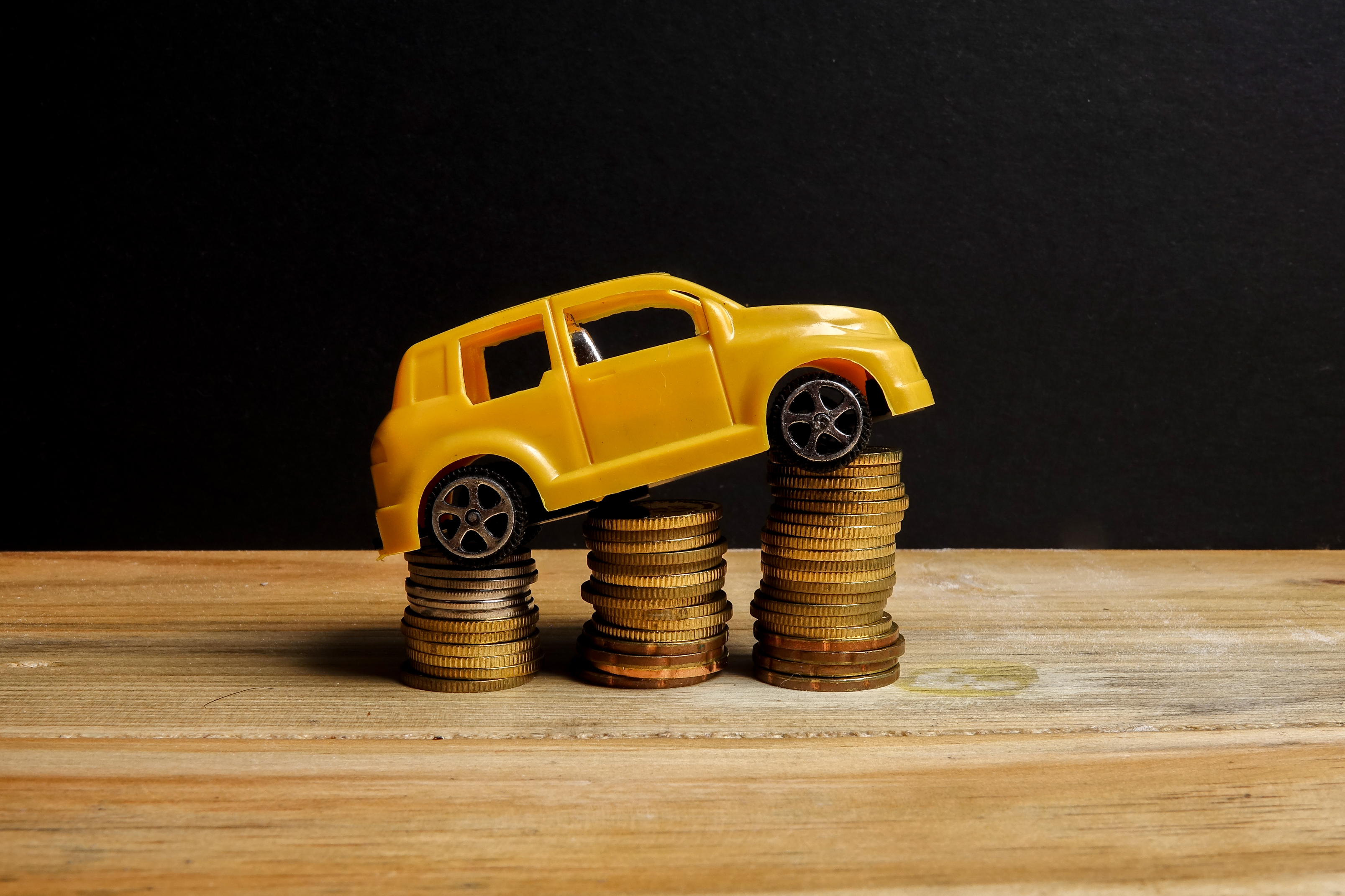 golden toy car on ascending stacks of coins
