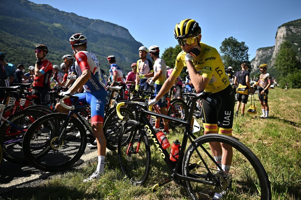 UAE Team Emirates teams Slovenian rider Tadej Pogacar C wearing the overall leaders yellow jersey and the pack of riders are temporarily immobilized by race regulators due to a demonstration by environmental protestors on the race route during the 10th stage of the 109th edition of the Tour de France cycling race 1481 km between Morzine and Megeve in the French Alps on July 12 2022 Photo by Marco BERTORELLO AFP Photo by MARCO BERTORELLOAFP via Getty Images