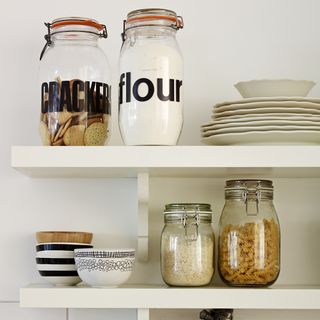 white shelf with food jars and plates