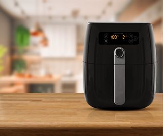 A black air fryer on a wooden countertop