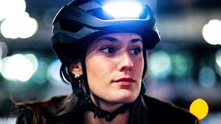 Women wearing a Lumos Ultra bike helmet with a built-in headlamp.