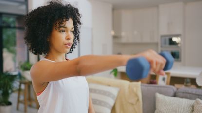 A woman exercising at home with dumbbells