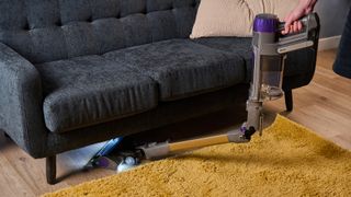 Shark PowerDetect cordless vacuum with wand bent forwards, cleaning under sofa