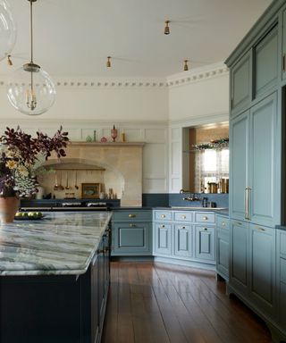 large kitchen with wooden floors, green kitchen cabinets and white walls with large island unit