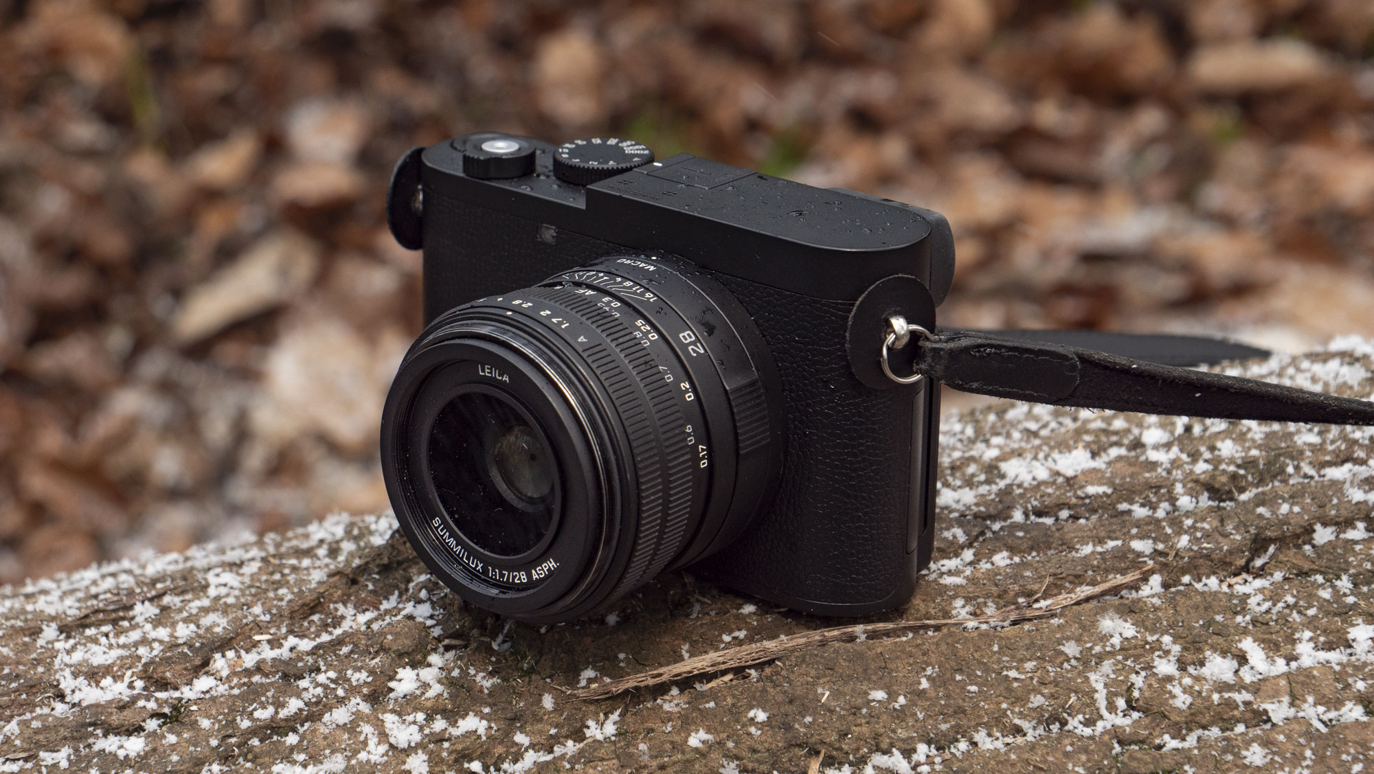 Leica Q3 Monochrom compact camera outside on a snow-dusted log