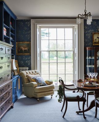 Dining room with blue wallpaper polished wood table and Georgian sash windows