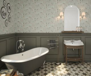 sage green bathroom with half height panelled walls, delicate floral wallpaper, green roll top bath
