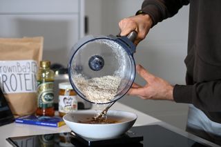 Male cyclist pouring oats from the blender as part of making banana bread