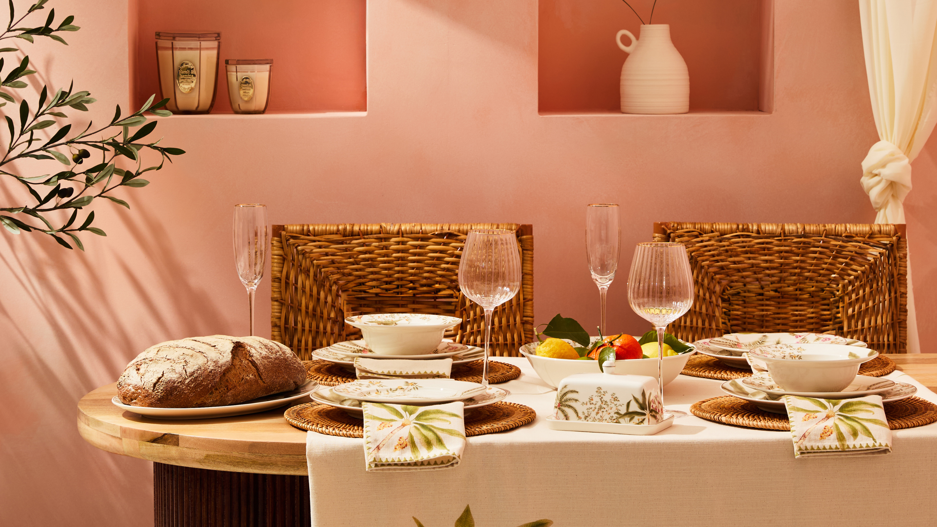Tropical-themed tableware on a wood table in a pink-painted room