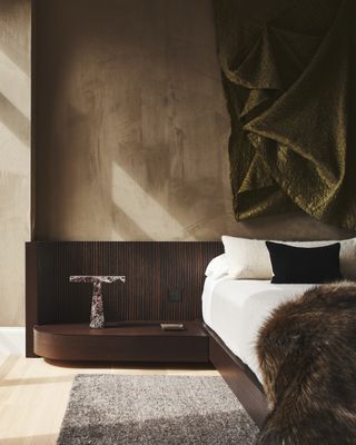 A brown bedroom with high pile throw and wooden headboard