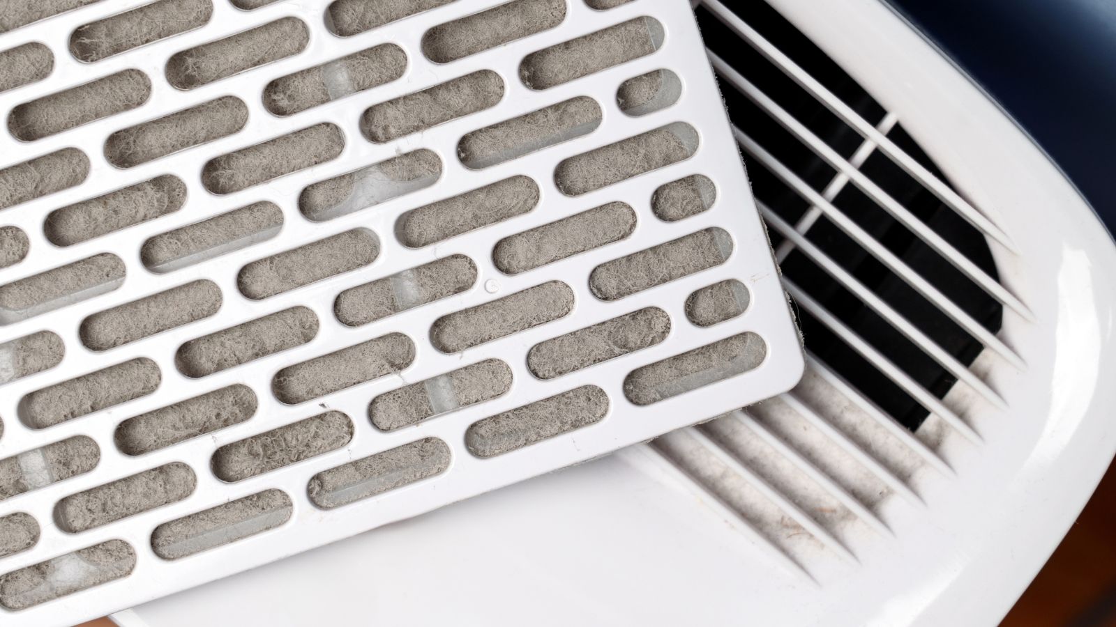 Dust clogged air filter cartridge on home dehumidifier panel.