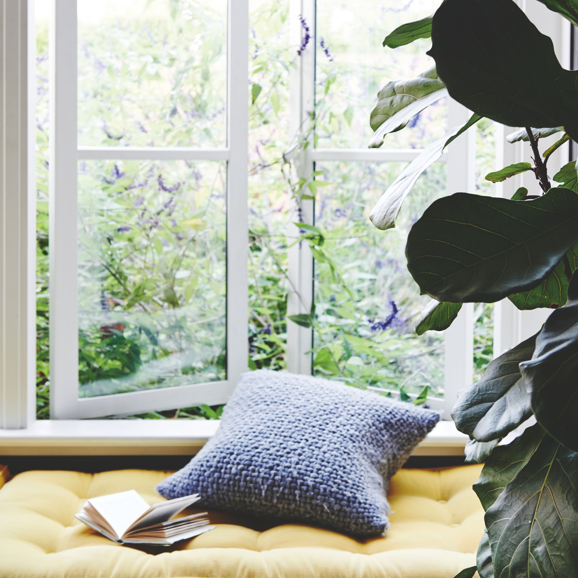 A window seat with a cushion and book