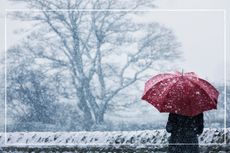 Woman with red umbrella sheltering in a wintery blizzard