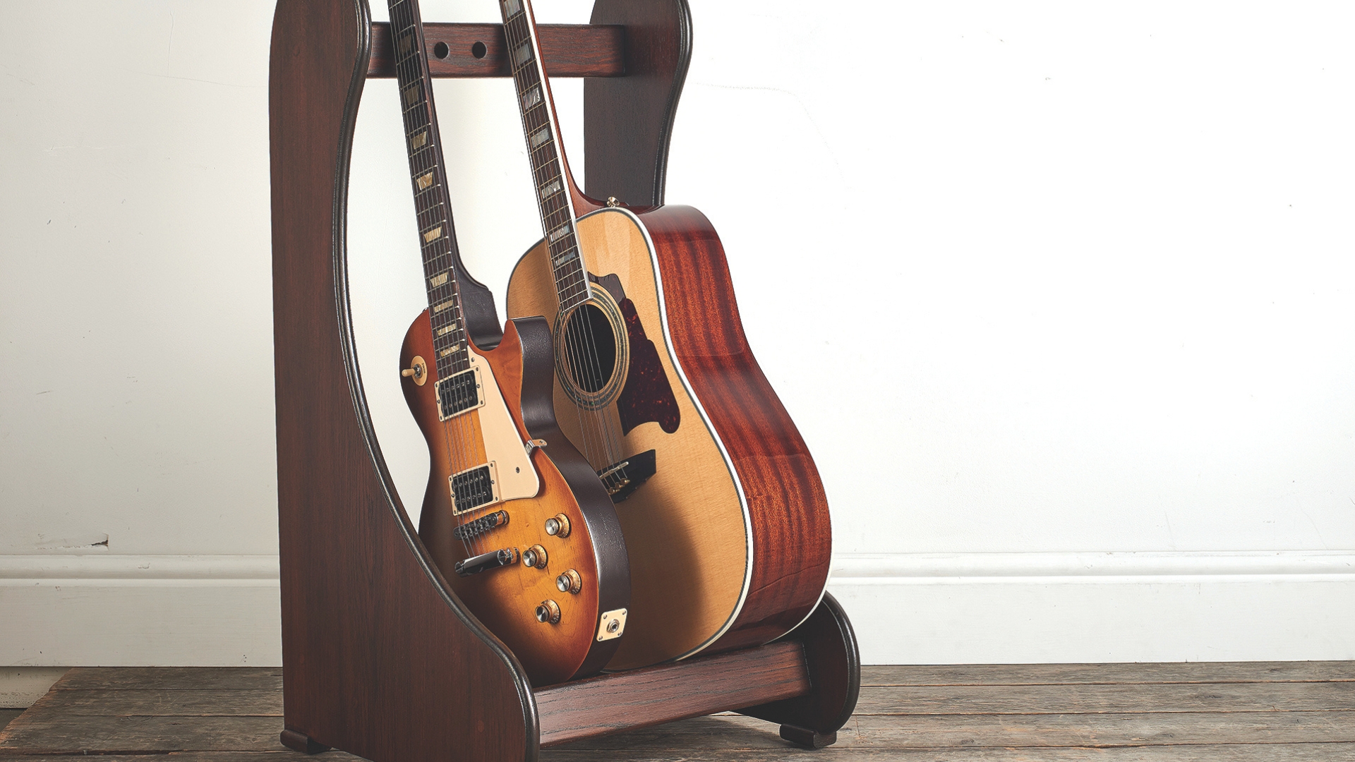 An electric and acoustic guitar on a guitar rack