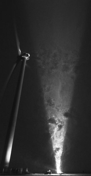 Traces of vortices shed from the turbine hub and tower behind a 2.5 MW wind turbine are visualized by the snowflakes illuminated in a light sheet parallel to the wind direction.