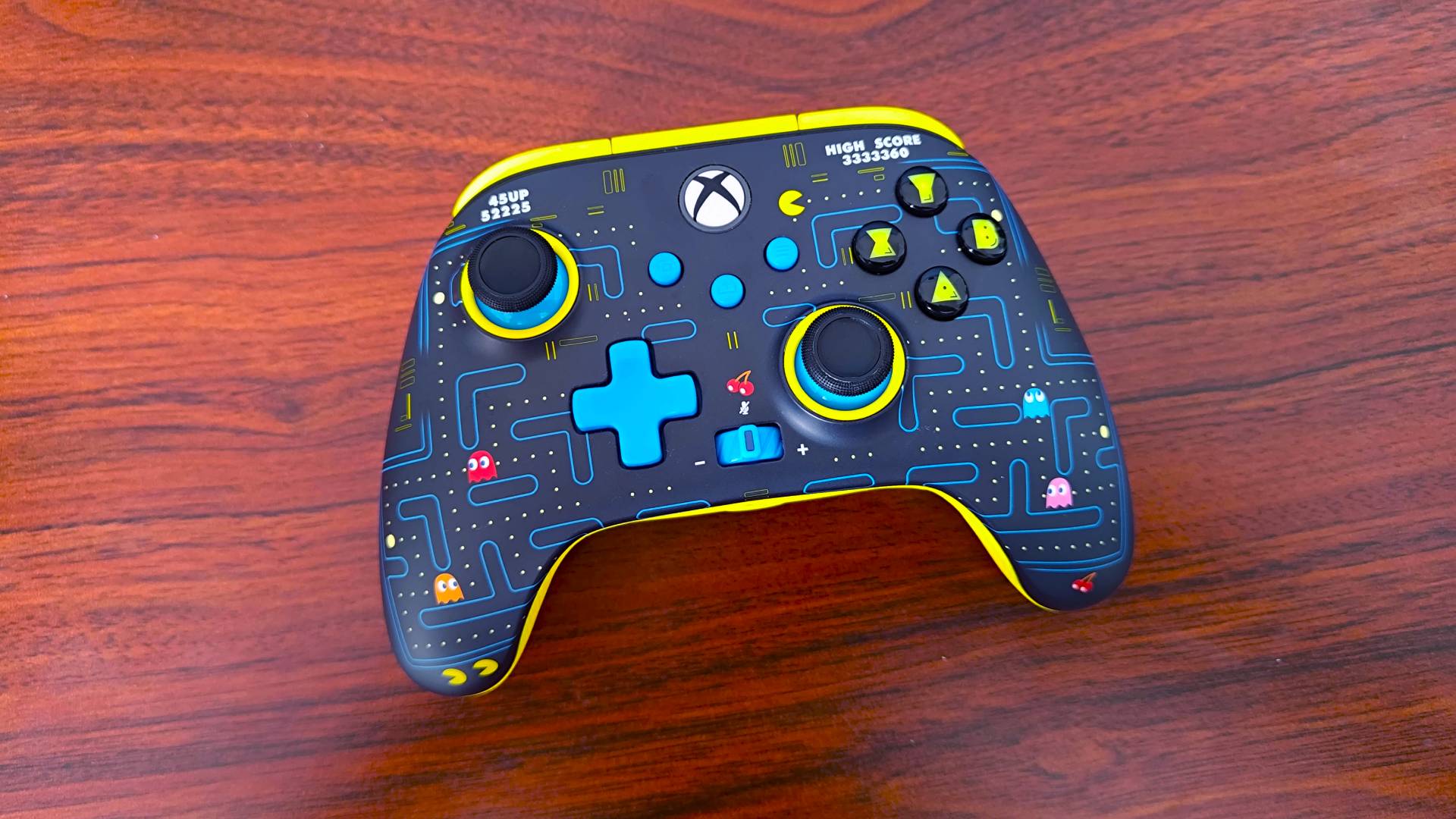 Pac-Man PowerA controller sitting on woodgrain desk.