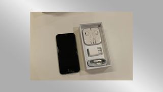 An Apple iPhone with headphones and plug included in the box