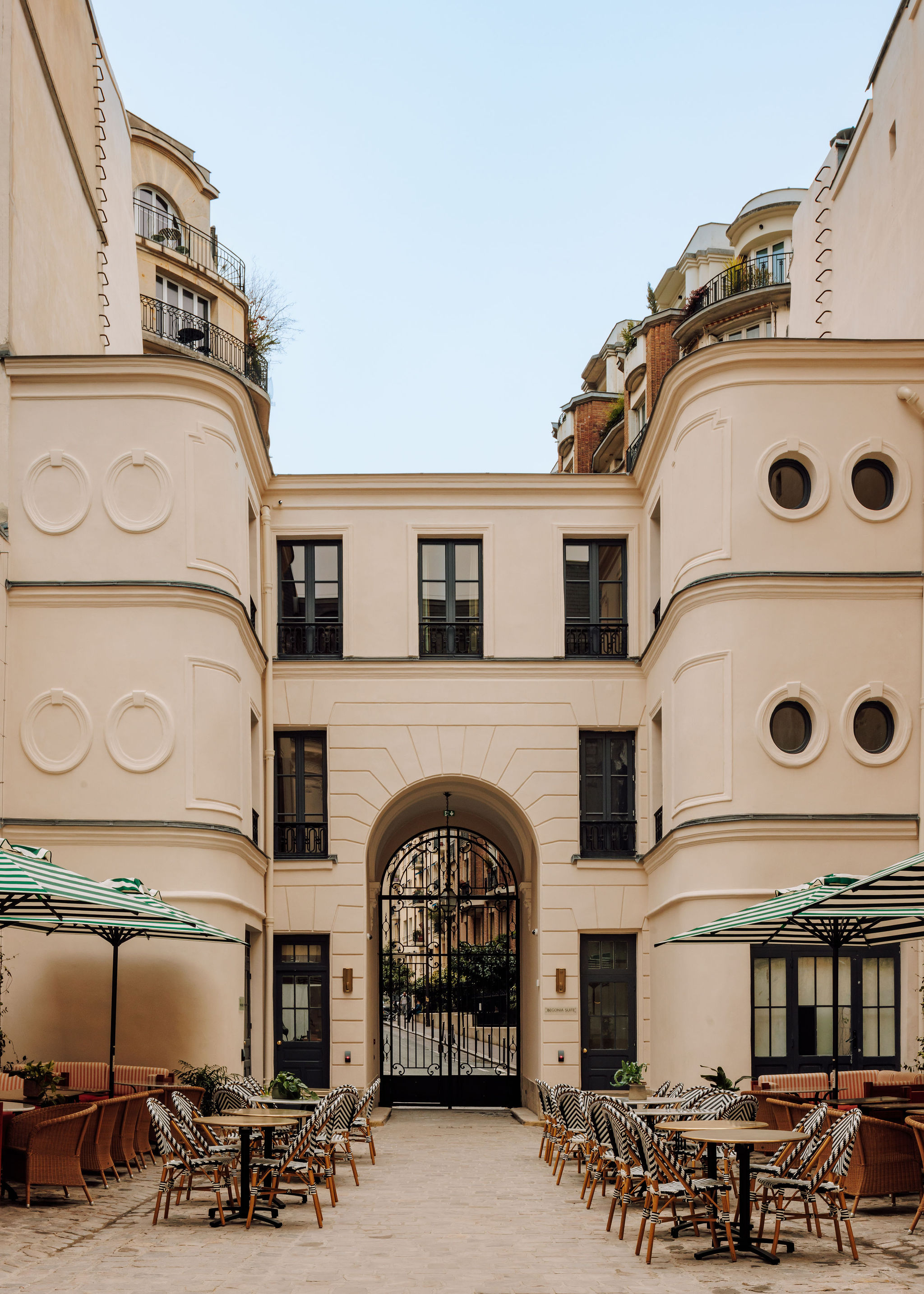 A Parisian hotel's exterior features an ornate, engraved surface painted in buttery and green tones, while inside, trailing plants and Art Deco furniture set the tone.