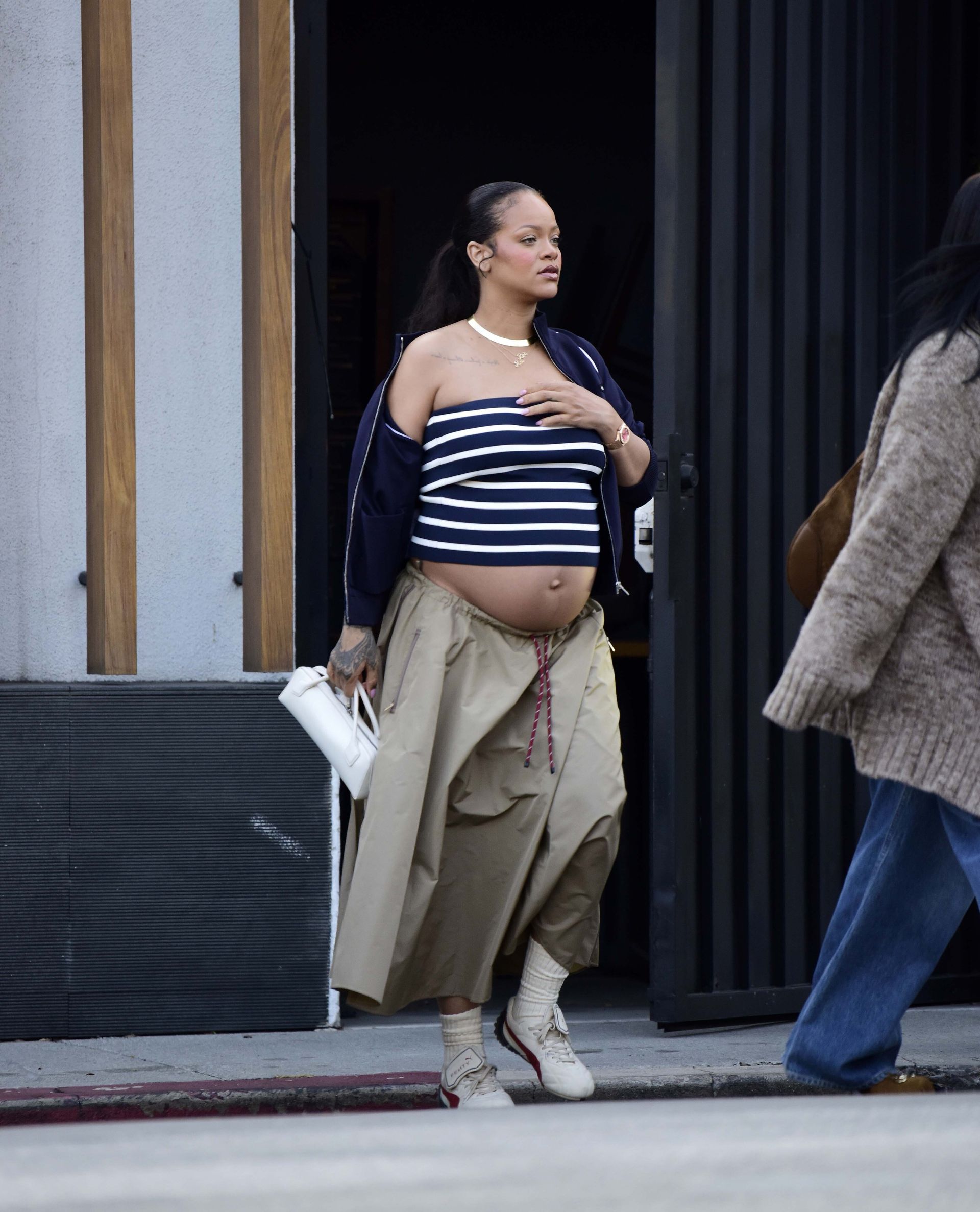 Rihanna wearing a striped top, khaki skirt, and sneakers