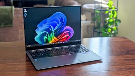 Samsung Galaxy Book5 Pro on a table with a green plant in the background. 