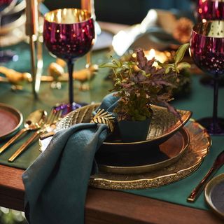 Gold and green christmas table setting with napkin and plants