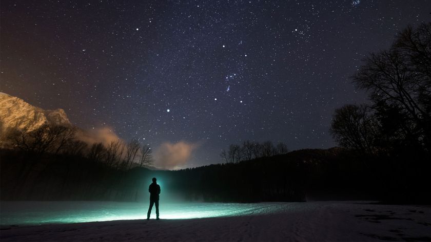 A person, with a glowing green outline, looking at the night sky with silhouetted hills.