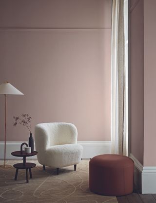 living area with pale pink walls, a boucle armchair and wooden coffee tables
