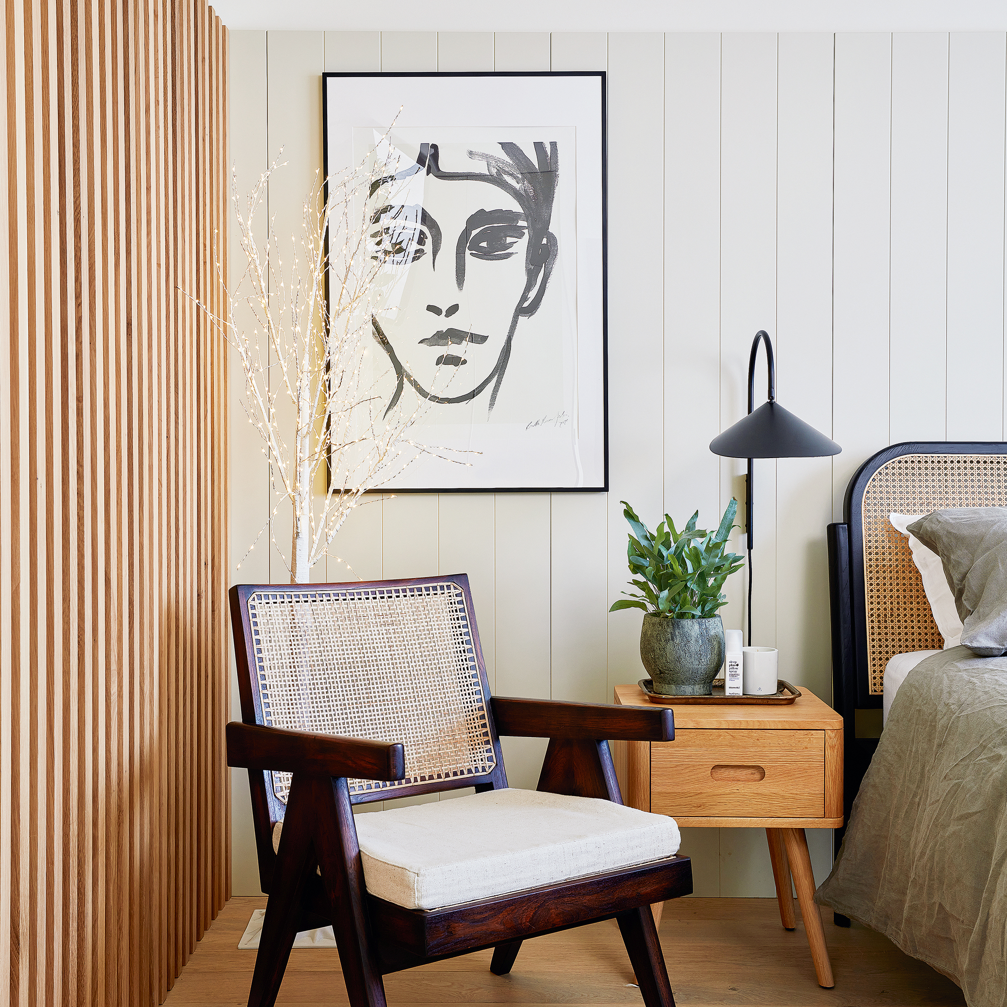 Bedroom with wall panelling, artwork, armchair and wall light