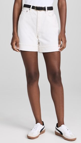 model wears white shorts with white belt and white shirt with puma sneakers 
